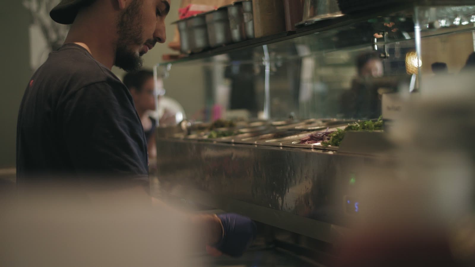 Chef plating in an open kitchen beside a wood-fired pizza oven